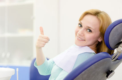 Woman giving a thumbs up from her dental chair